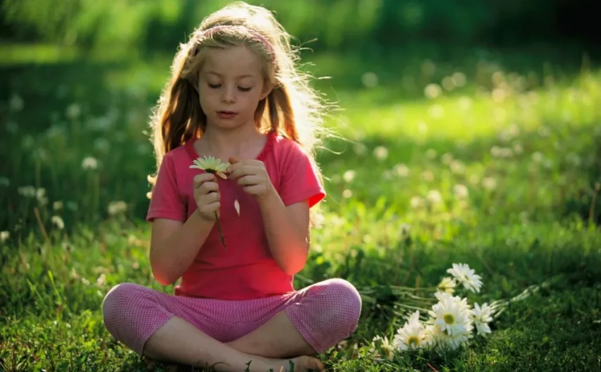 bambina seduta su un prato in mezzo alla natura