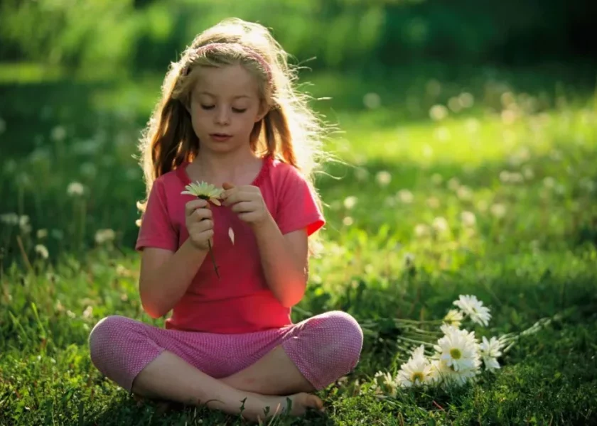 bambina seduta su un prato in mezzo alla natura