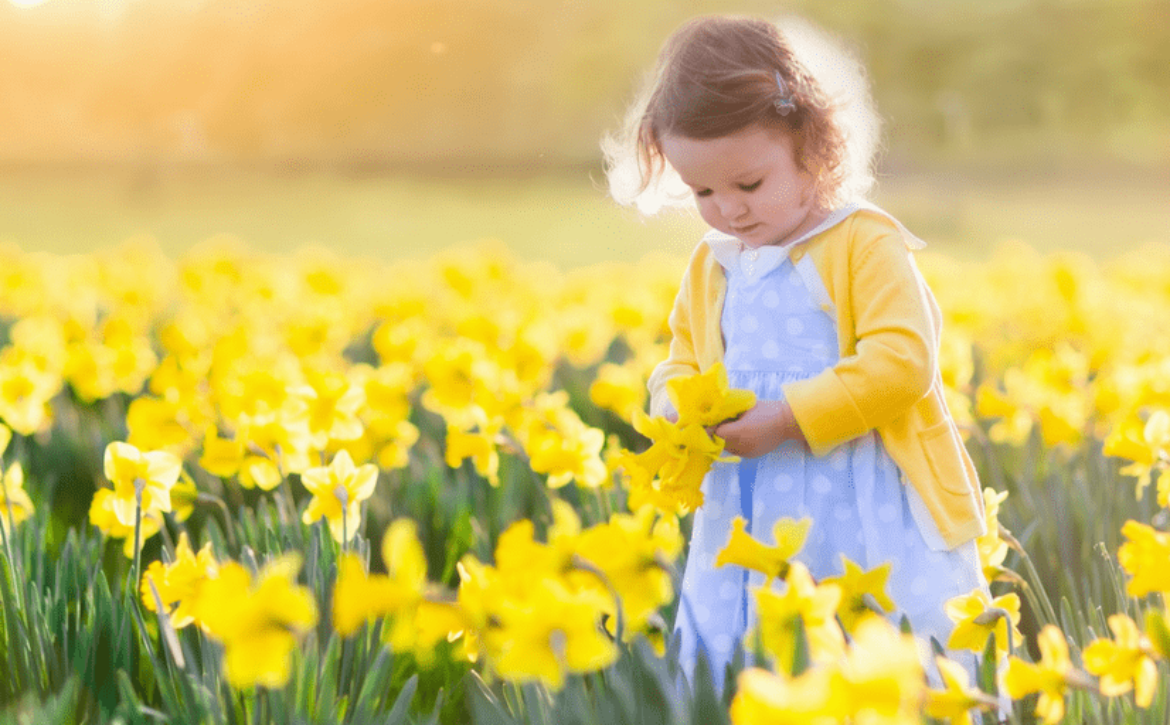 bambina in mezzo ad un prato di fiori in primavera con i pidocchi