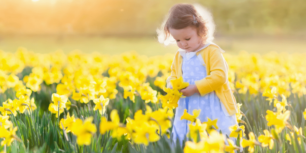 bambina in mezzo ad un prato di fiori in primavera con i pidocchi